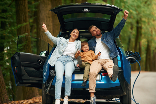 family sitting on trunk of car